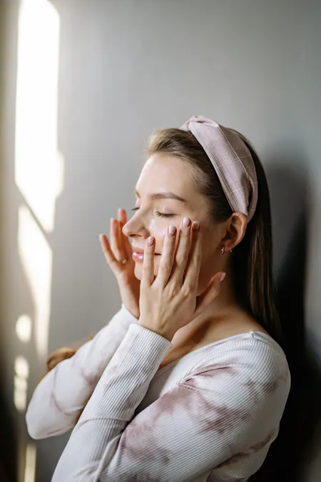 Woman enjoying a skincare routine in natural window light